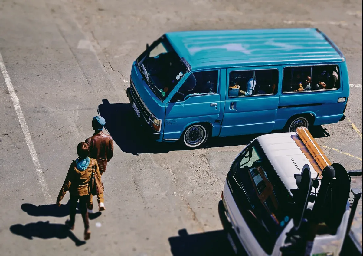 A minibus taxi working a Maboneng street in rush-hour traffic, hand out for passengers